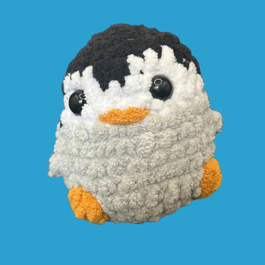 Small plush toy resembling a penguin on a blue background